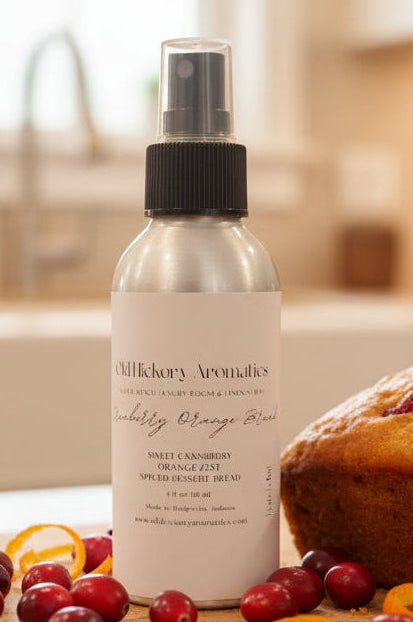 Spray bottle of Old Hickory Aromatics Cranberry Orange Bread Room and Linen Spray on a table with fresh cranberries, orange zest, and a loaf of sweet bread.