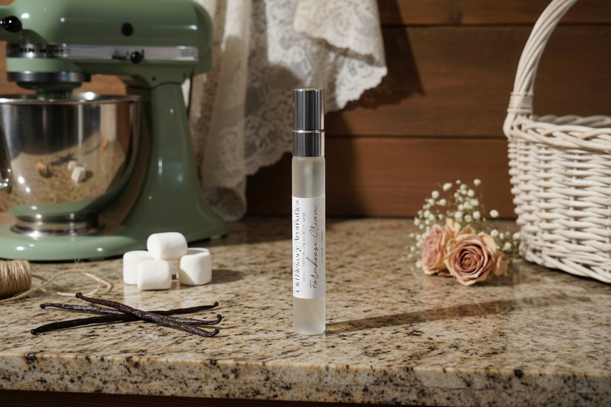 Small bottle of Old Hickory Aromatics body mist on a granite farmhouse kitchen counter with marshmallows, vanilla beans, a stand mixer, flowers, and basket in the background. 