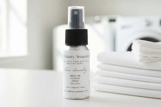 Small Old Hickory Aromatics Clean Laundry Room and Linen Spray bottle on a laundry room counter with folded white sheets and white front load washer and dryer in background. 
